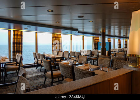 Ein Abendessen Sitzecke auf einem Kreuzfahrtschiff mit großen hellen Fenstern, Gold und Braun gemusterte komfortable Stühle, Braun geometrisch gemusterten Teppich und Curv Stockfoto