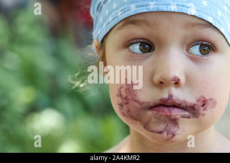 Portrait von ein nettes Mädchen mit einem schmutzigen Mund nach dem Essen mulberry Beeren Stockfoto