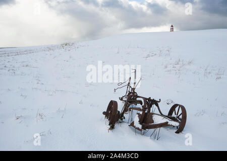Rusty landwirtschaftliche Maschine. Leuchtturm im Hintergrund. Alnes, GodÂØya. Stockfoto