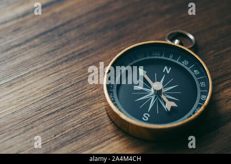 Eine einzige Goldene Kompass oben auf einem hölzernen Schreibtisch Stockfoto