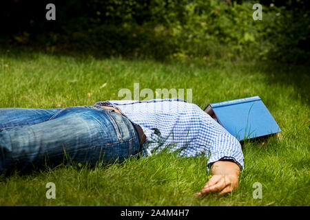 Frau liegend im Gras. Schlafen mit Buch über Gesicht. Entspannt. Stockfoto