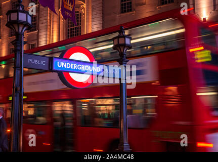 LONDON, UK, 17. JUNI 2013: Beleuchtete London U-Schild am Piccadilly Circus Station Eingang mit dem Doppeldeckerbus bewegt sich entlang der Stockfoto