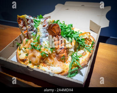 Eine schlange Pizza (hummerschwänze, geräucherter Lachs, Garnelen, Krabben) von steveston Pizza Company in Steveston Village, Richmond, British Columbia, Kanada. Stockfoto