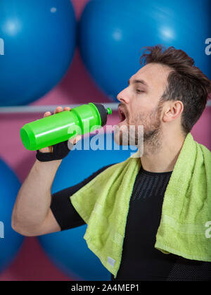 Portrait einer jungen passt man das Trinken aus einer Plastikflasche in einem Fitnessstudio Stockfoto