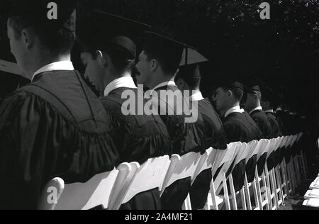 1964 saßen männliche Studenten in akademischen Gewändern und Mortarboards bei der Abschlussfeier der University of Southern California (USC), Los Angeles, Kalifornien, USA. Stockfoto