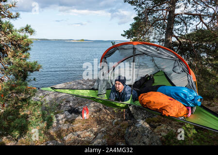 Der Mensch ruht in der Hängematte am Seeufer Stockfoto