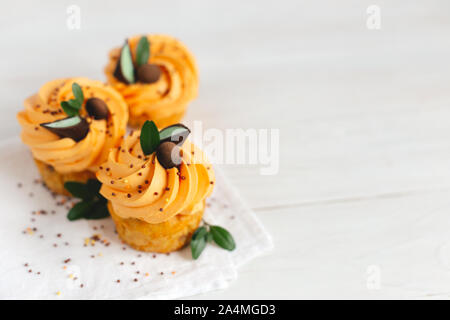 Lecker Kürbis Cupcakes mit orange Creme und Dekoration auf weiße Holztisch. Für Text platzieren. Stockfoto