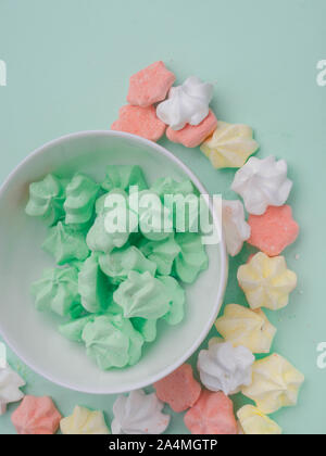Keramische Schüssel voller bunter merengues in Pastell mint Hintergrund Stockfoto