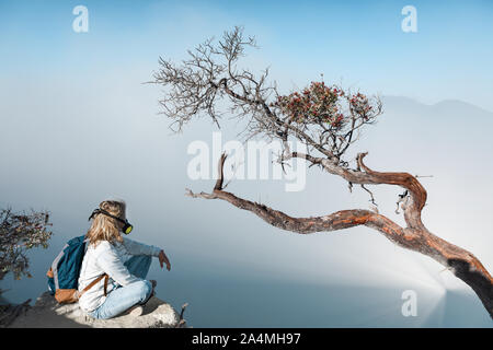 Junge Frau in Schutzmaske auf dem Gipfel des aktiven Vulkan Kawah Ijen Krater oben Säure See mit giftigen Dämpfe. Beliebtes Reiseziel. Stockfoto