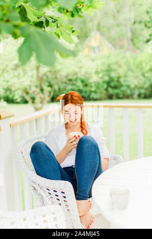 Junge Frau ruht auf dem Balkon Stockfoto