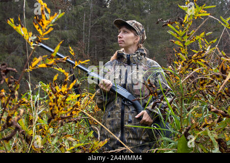 Frau Jäger in Camouflage mit Gewehr auf der Riverside Stockfoto