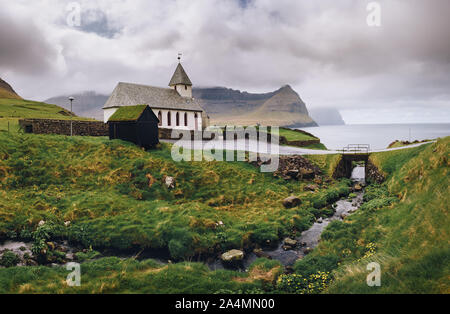 Kleines Dorf Kirche am Ufer des Meeres in Vidareidi, Färöer, Dänemark Stockfoto