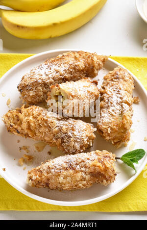 Frittierte Bananen auf die Platte über der weißen Stein Hintergrund. Leckere Dessert von Gebratene Bananen im asiatischen Stil. Stockfoto