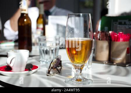 Tasse Kaffee und ein Glas Bier auf den Tisch im Restaurant bei Sonneneinstrahlung Stockfoto