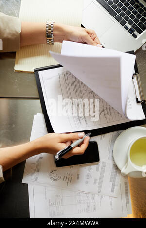 Nahaufnahme der Geschäftsfrau, die an ihrem Arbeitsplatz sitzen, lesen und Signieren von Dokumenten Stockfoto