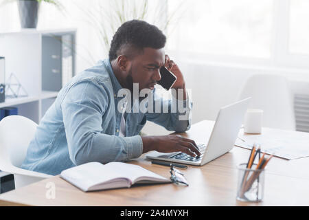 Besorgt Geschäftsmann mit Mobiltelefon und Laptop Bildschirm Stockfoto