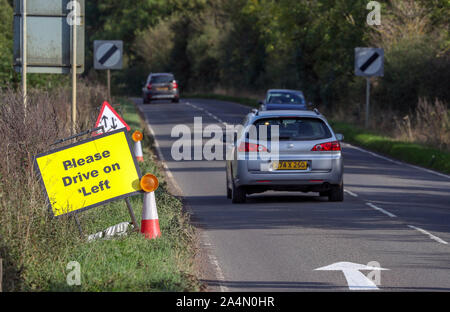 Ein Fahrzeug mit diplomatischen Platten übergibt einen Fahren Sie bitte auf der linken Seite anmelden und signalisieren, dass auf der B 4031 außerhalb der RAF Croughton platziert wurden, in Northamptonshire, wo Harry Dunn, 19, starb, als sein Motorrad in einem Kopf beteiligt war - auf Kollision im August. Stockfoto