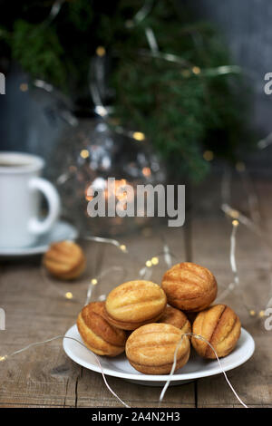 Hausgemachte Kekse Kekse in der Form von Muttern auf dem Hintergrund einer Tasse Kaffee, Tannenzweigen und Girlanden. Stockfoto