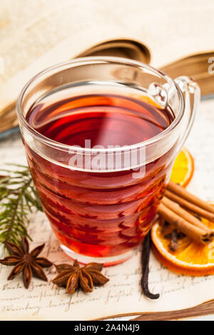 Glühwein mit Gewürzen auf einem alten Kochbuch Stockfoto