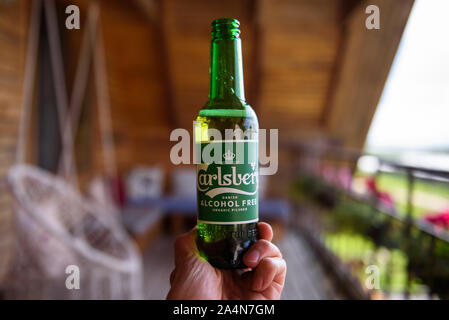 LUBANA, Lettland. 1. August, 2019. Ein Mann hält in der Hand eine Flasche Carlsberg Alcochol Freie organische Bier. Stockfoto