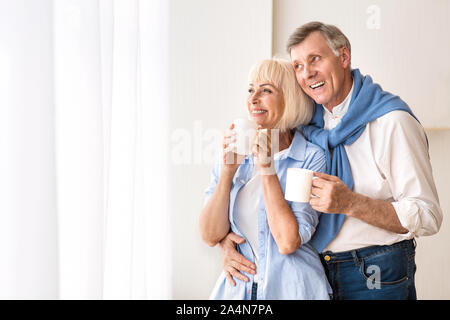 Liebevolle senior Paar in der Nähe von Fenster und Tee trinken. Stockfoto