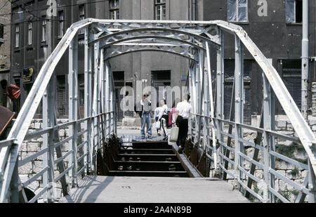 5. Juni 1993 während der Belagerung von Sarajevo: Nach sammeln Trinkwasser aus einem Standrohr, bosnische Muslime vorsichtig wieder in die Innenstadt über was der Ćumurija Brücke links ist. Stockfoto