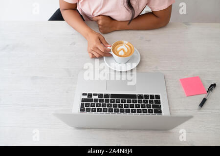 Frau mit Kaffee vor Laptop Stockfoto