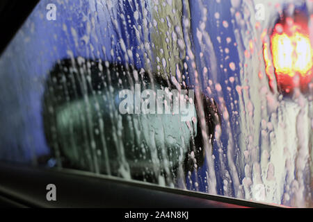 Innerhalb einer Autowaschanlage, die Auto gereinigt. Auf diesem Foto sehen Sie die Fenster mit einigen Blasen und Wasser bedeckt. Stockfoto