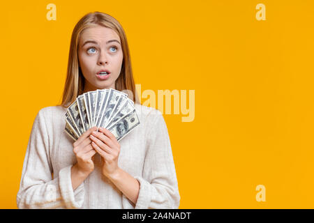 Nachdenkliches Mädchen, dass Bündel von Dollar und Nach oben Suche Stockfoto