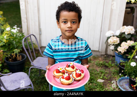 Junge Halteplatte mit Cupcakes Stockfoto