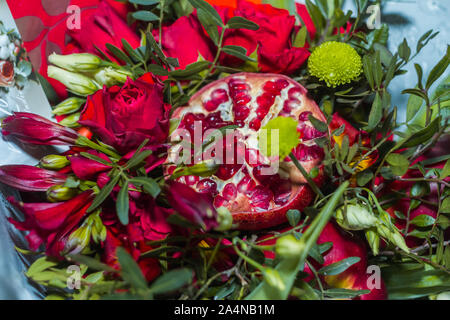 Originelles Geschenk in Form von einem Blumenstrauß aus Rosen, Granatäpfel, Pflaumen, Trauben auf einem weißen Hintergrund. Ansicht von oben Stockfoto