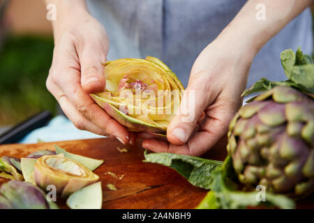 Person schneiden frische Artischocken Stockfoto