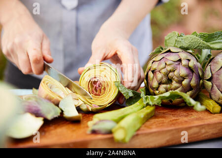 Person schneiden frische Artischocken Stockfoto