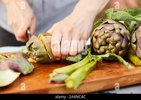 Person schneiden frische Artischocken Stockfoto