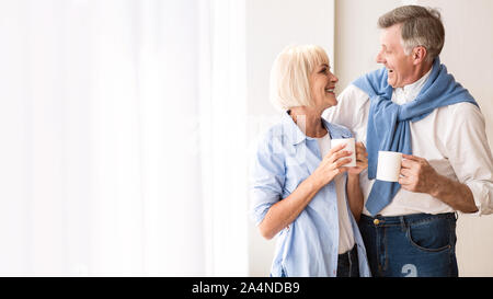 Gerne älteres Ehepaar miteinander reden in der Nähe der Fenster und Tee trinken. Stockfoto