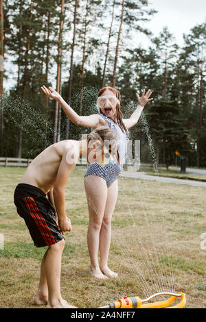 Jungen und Mädchen spielen mit Wasser Stockfoto