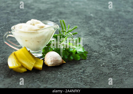 Tartar Sauce in einem Glas Soße Boot mit Zutaten auf einem schwarzen Hintergrund. Kopieren Sie Platz. Stockfoto