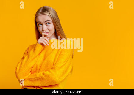 Portrait von zweifelhafter Jugendmädchen über orange Hintergrund Stockfoto