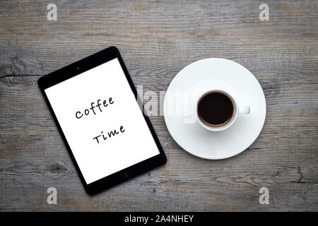 Tasse Kaffee mit Bohnen auf einem Holztisch mit einem Tablett mit 'Kaffee' Meldung Stockfoto