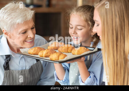 Fröhliches Mädchen Holding und riechen frisch gebackene Croissants Stockfoto