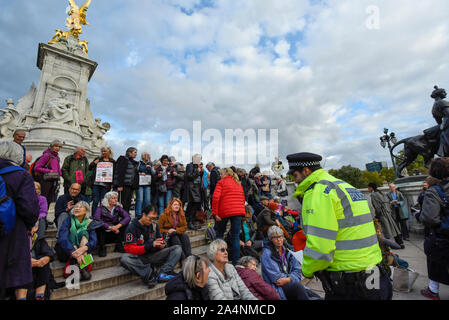 London, Großbritannien. 15. Oktober 2019. Ein Polizeioffizier liest einen Abschnitt 14 Vorankündigung Klima Aktivisten vor dem Aussterben Rebellion Inszenierung eines Großeltern Protest auf der Queen Victoria Memorial außerhalb des Buckingham Palace. Die Aktivisten fordern von der Regierung auf, unverzüglich Maßnahmen gegen die negativen Auswirkungen des Klimawandels zu ergreifen. Credit: Stephen Chung/Alamy leben Nachrichten Stockfoto