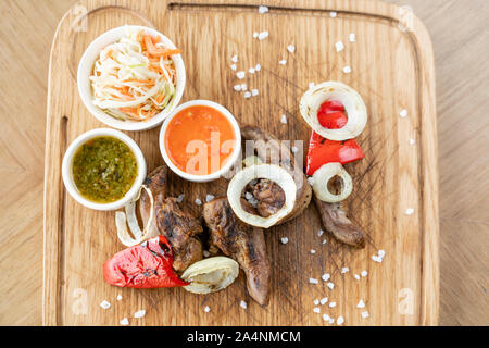 Lamm Zunge Kebab mit Sauerkraut und zwei Saucen. Serviert auf einem Holzbrett. Grill Restaurant Menü, eine Reihe von Fotos von verschiedenen Fleischsorten. Stockfoto