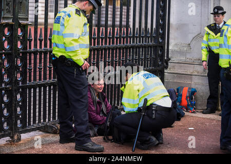 London, Großbritannien. 15. Oktober 2019. Polizei in Anwesenheit als Klima Aktivist aus Aussterben Rebellion sitzt mit Handschellen gefesselt, vor, verhaftet zu werden, außerhalb der Tore zum Buckingham Palast, während einer Großeltern protestieren. Die Aktivisten fordern von der Regierung auf, unverzüglich Maßnahmen gegen die negativen Auswirkungen des Klimawandels zu ergreifen. Credit: Stephen Chung/Alamy leben Nachrichten Stockfoto