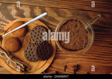 Milch und Cookies auf dem Tisch. Glas Becher mit Schokolade Milch auf Holztisch und in der Nähe liegt Schokolade Kekse auf einer Holzplatte. Ansicht von oben Stockfoto
