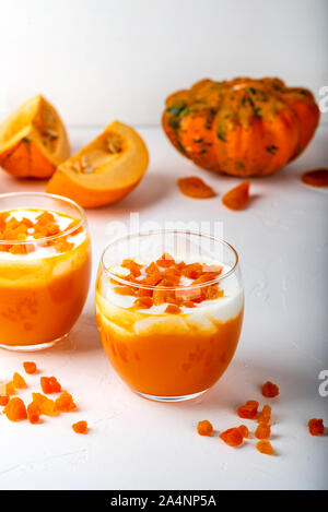 Kürbis roh Dessert. Kürbis Smoothie mit Joghurt und getrocknete Aprikosen in Gläsern auf einem weißen Hintergrund. Close-up. Stockfoto