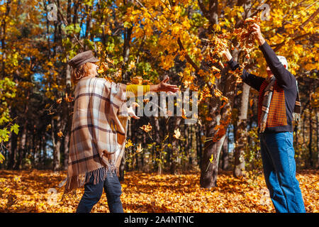 Herbst Jahreszeit. Paar Blätter im Herbst Wald werfen. Senior Familie Spaß im Freien Stockfoto