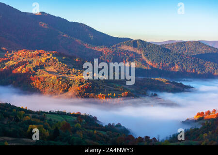 Schönen Herbst Landschaft mit Tal Nebel. Wunderbare Natur Landschaft bei Sonnenaufgang. Bergkette in der Ferne. Stockfoto