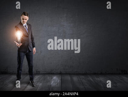 Vorderansicht des Geschäftsmannes und Holding leuchtende Glühbirne in der Hand Stockfoto