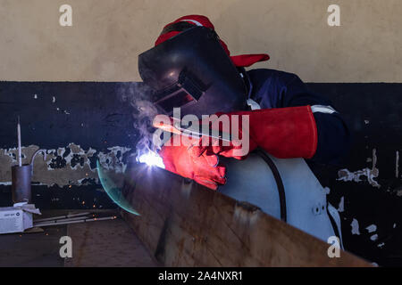 Motswana Schweißgerät Arbeiter in einer Botswana Workshop, Schweißen zwei Teile aus Metall Stockfoto