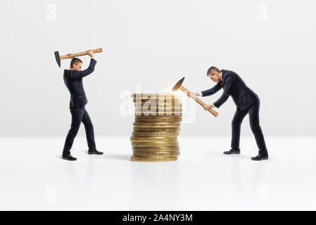 Seitenansicht der Unternehmer Absturz großen goldenen Münzen mit Hammer stack, auf weißem Hintergrund Stockfoto